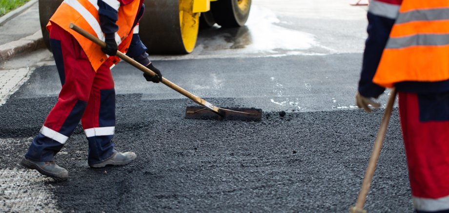 The road workers' working group updates part of the road with fresh hot asphalt and smoothes it for repair.