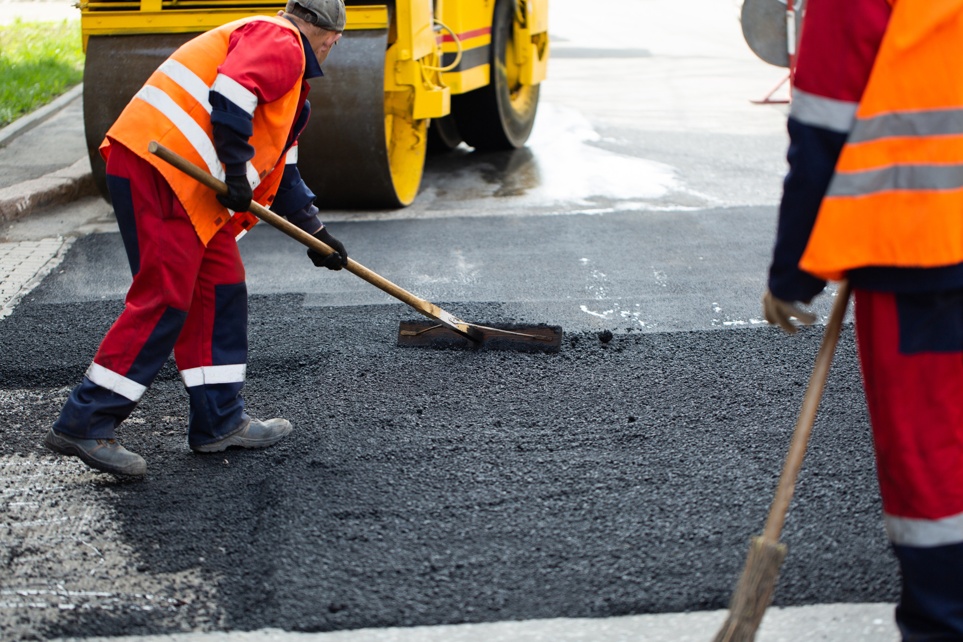 The road workers' working group updates part of the road with fresh hot asphalt and smoothes it for repair.
