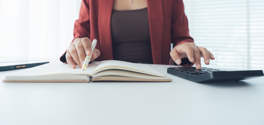 Busy Accountant: A sharp photo captures an accountant diligently focused on finances, with a calculator in one hand and a pen poised over a ledger in the other.