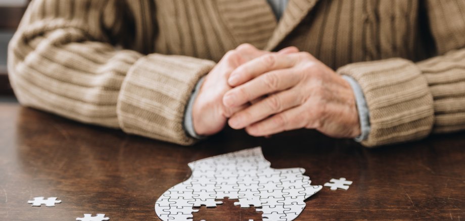 cropped view of senior man playing with puzzles on table