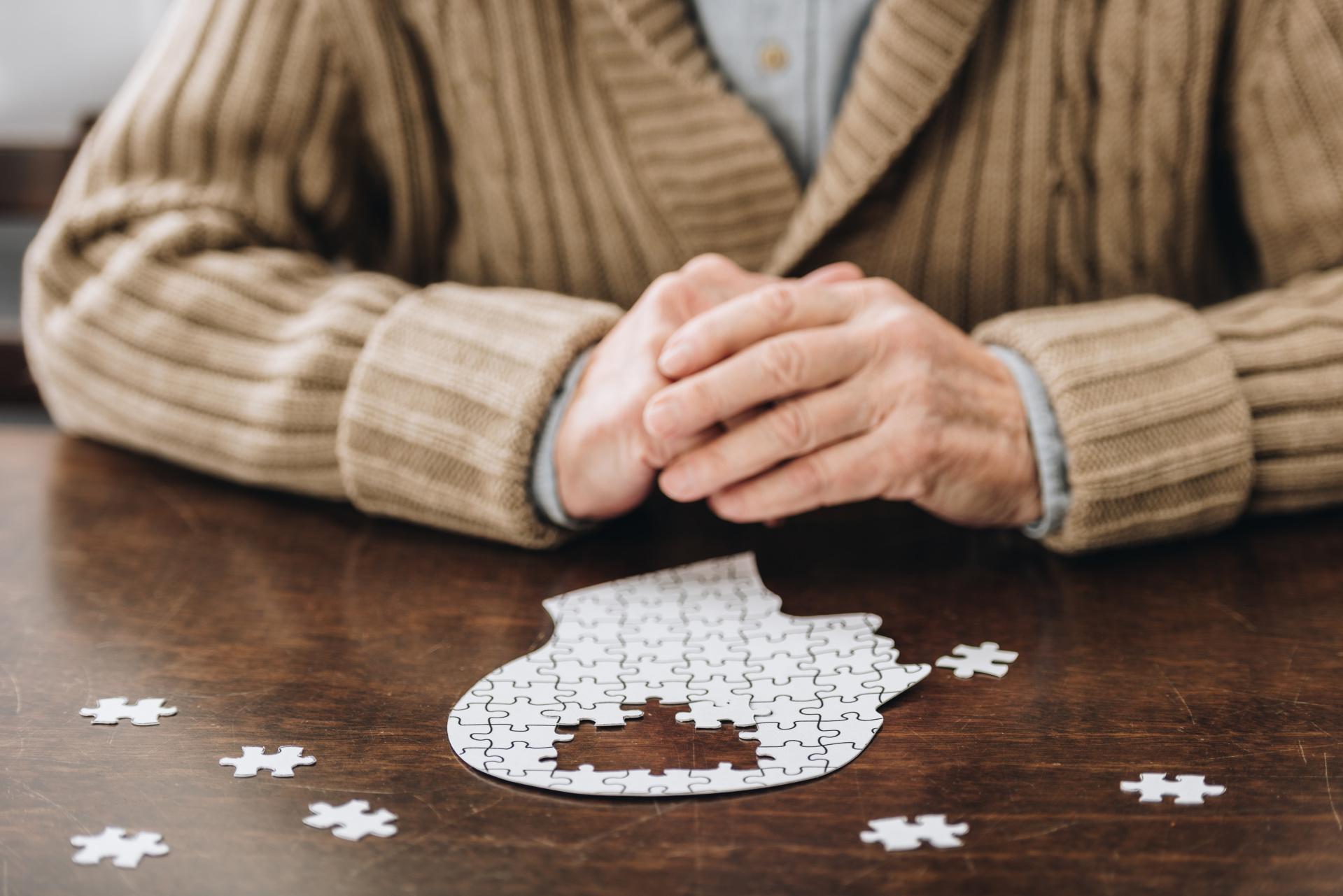 cropped view of senior man playing with puzzles on table cropped view of senior man playing with puzzles on table